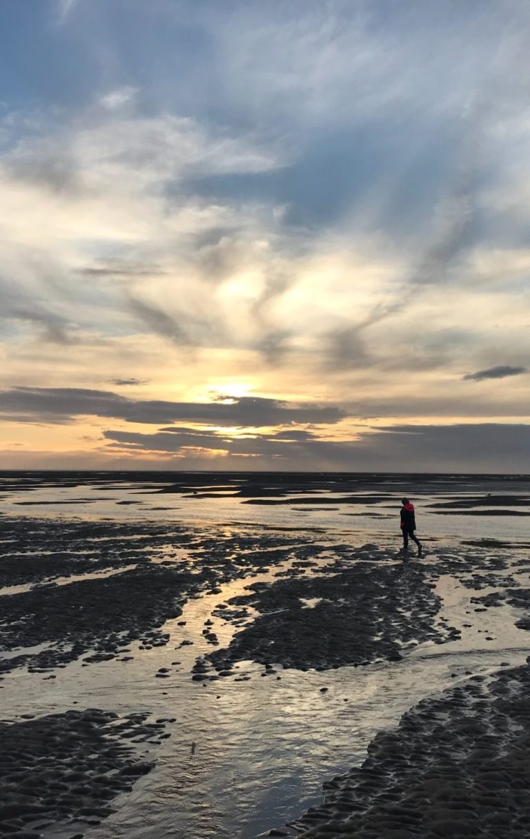 Liza on Fleetwood beach. Woman walking on a wet Fleetwood beach at sunset