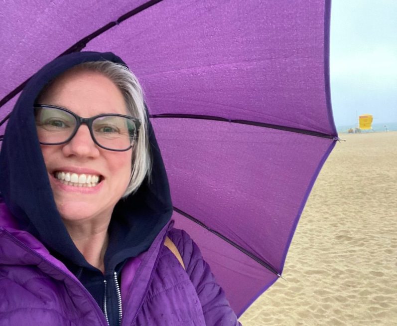 Liza sailing a boat. A woman at the helm of a boat, smiling for the camera.